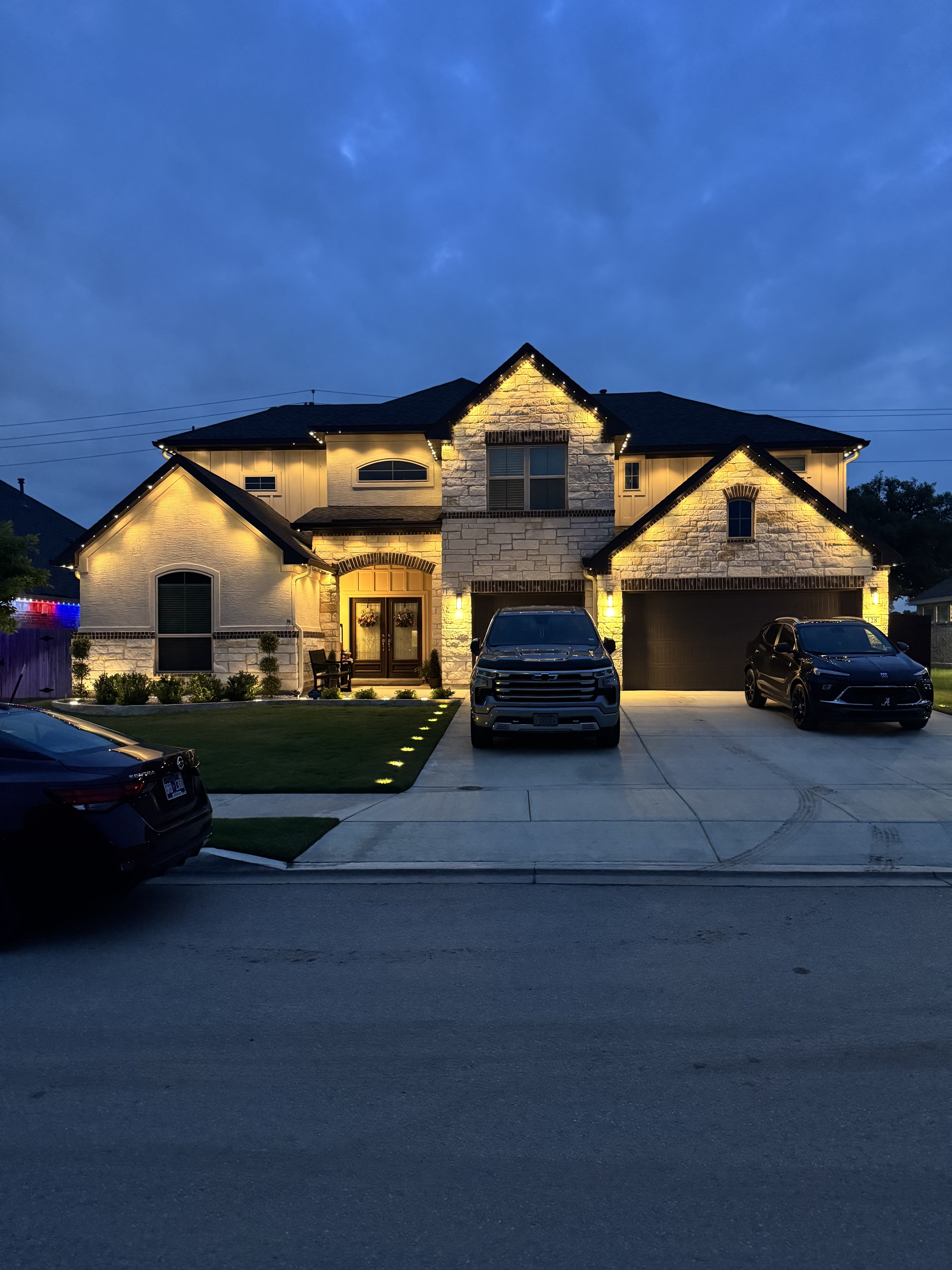 White-stucco Texas home with champagne-cream roofline lighting at twilight