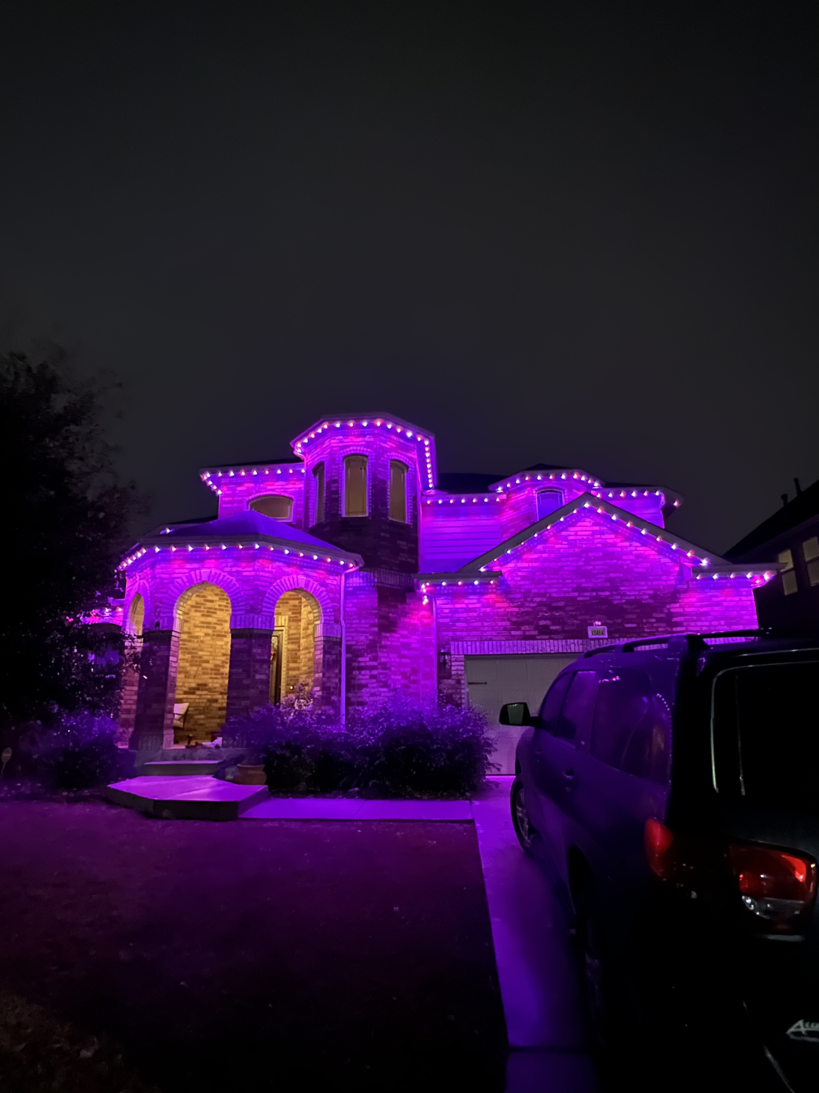 San Antonio brick home washed in magenta-pink permanent LED lighting at night