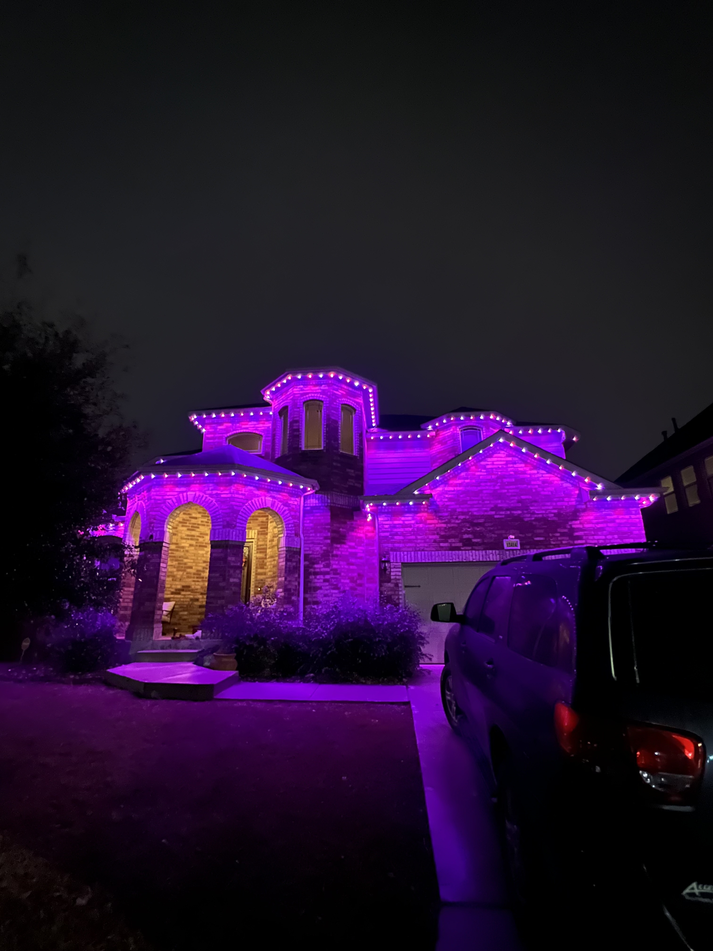 Texas brick home with royal purple permanent LED wash and warm interior glow