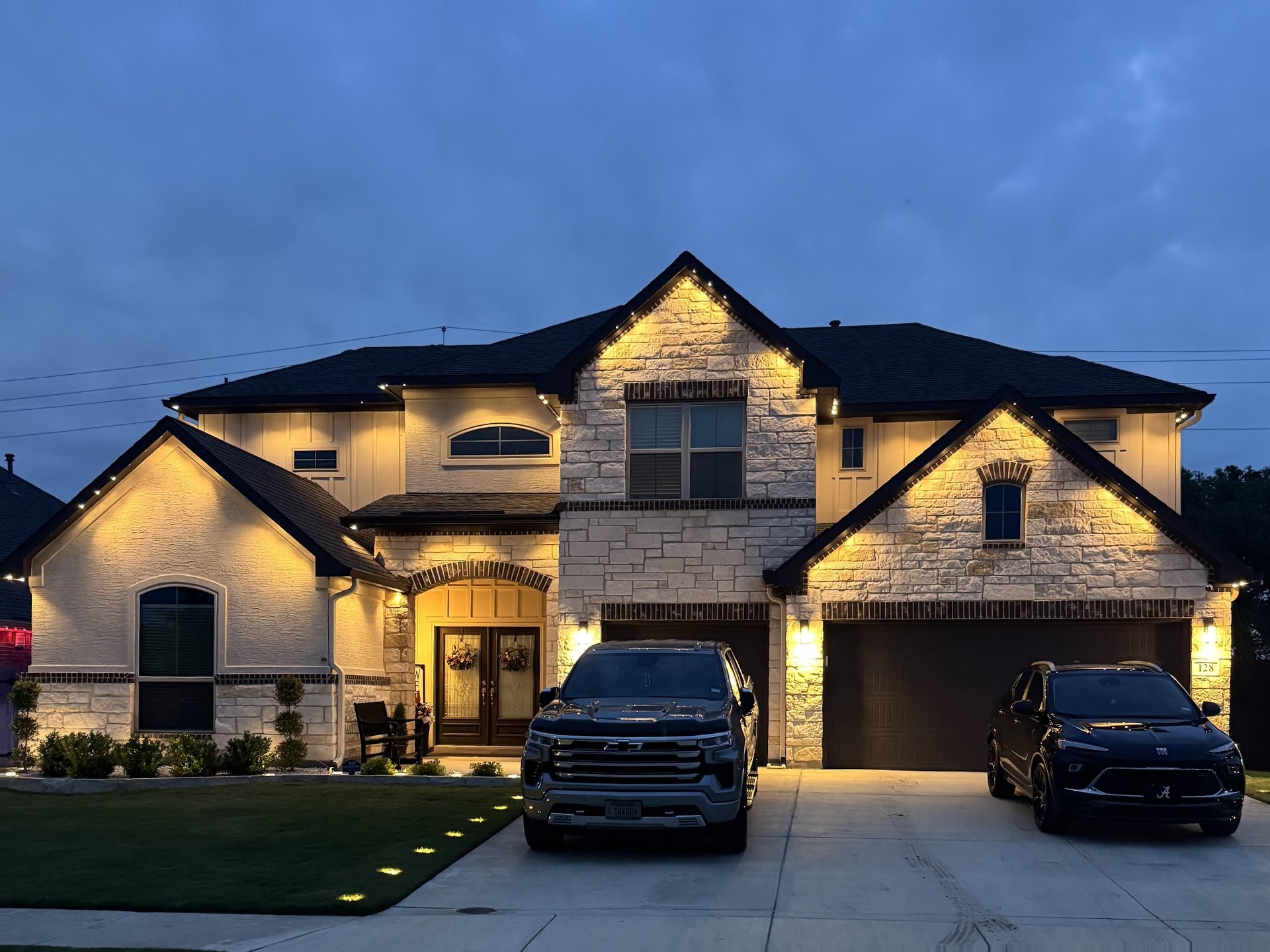 White-stucco Texas home with warm white permanent LED roofline lighting at dusk
